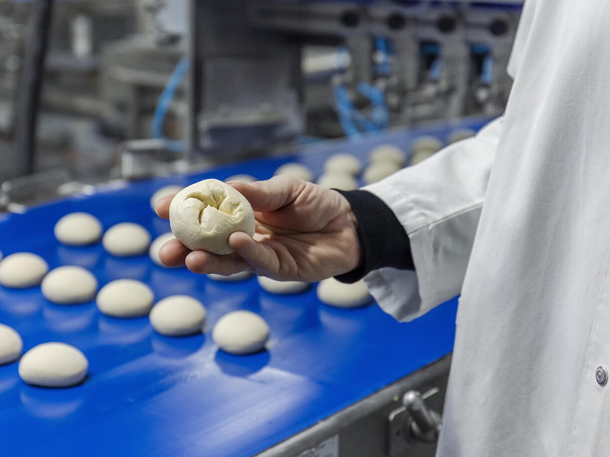 Mitarbeiter hält ein Teigballen in der Hand