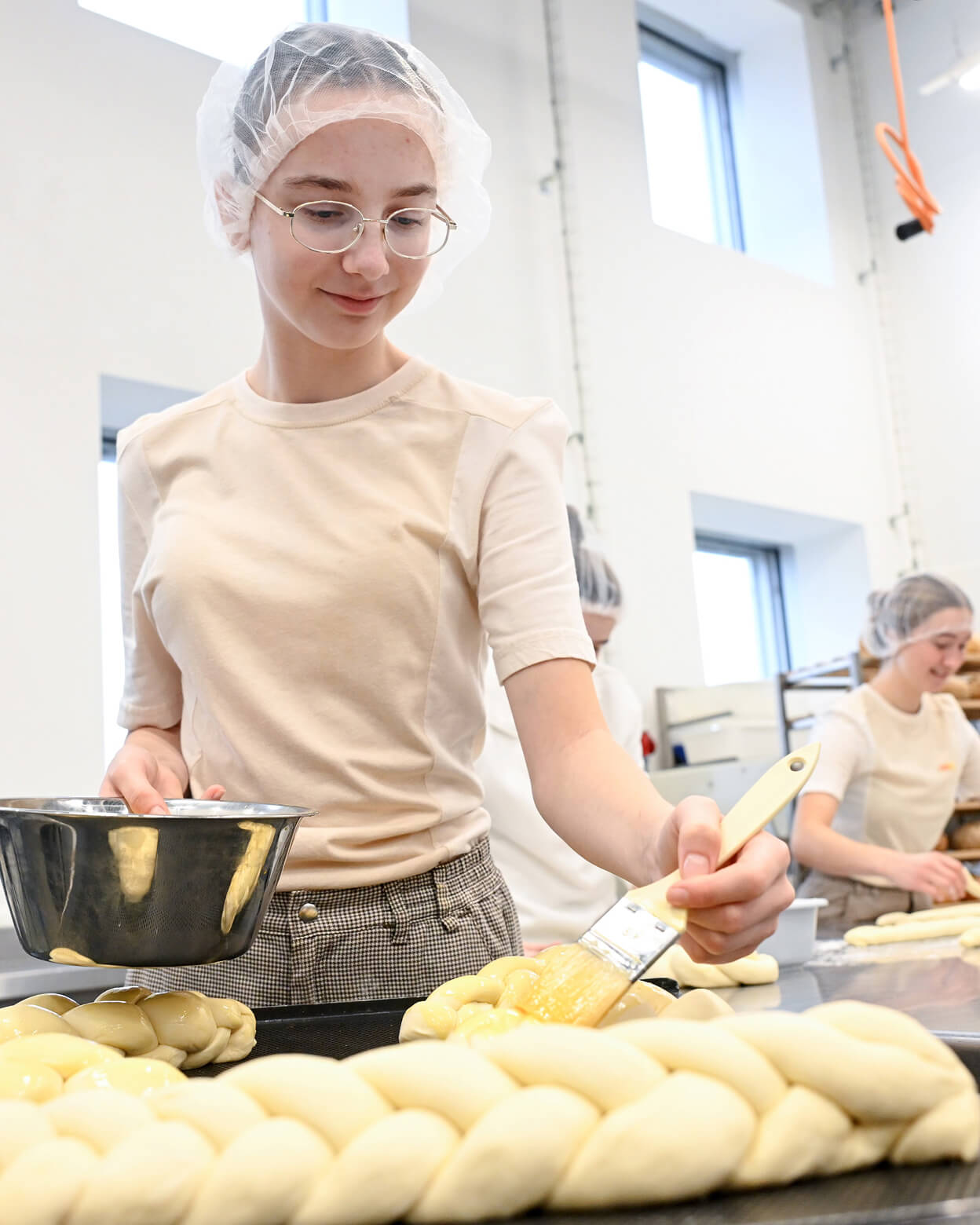Lernende bestreicht Zopf mit Eigelb