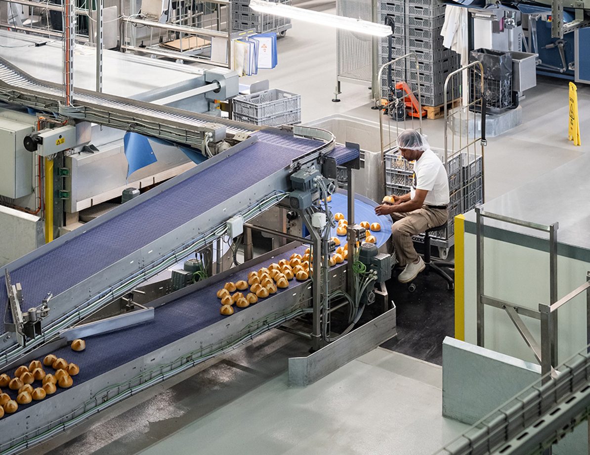 Mitarbeiter vor Fliessband und Brötchen